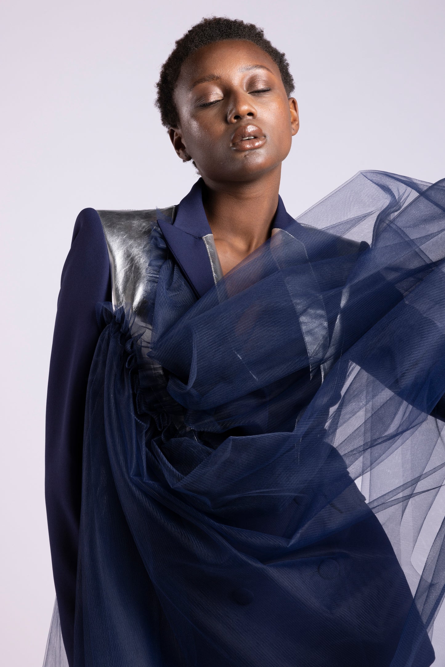 Tailleur da donna su misura con giacca doppio petto in cady blu notte e inserti in pelle argento specchiata e mantella monospalla in tulle