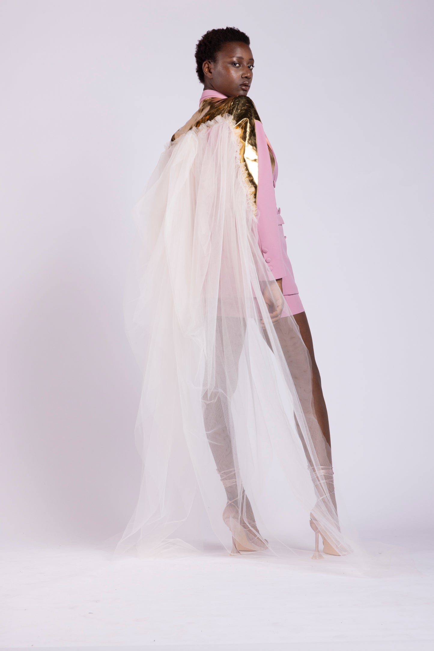 Tailleur da donna su misura con giacca doppio petto in cady rosa e dettagli in pelle oro specchiata con gonna in cady e pelle e mantello in tulle primavera estate